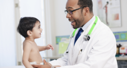 A friendly pediatrician smiles at a happy baby boy